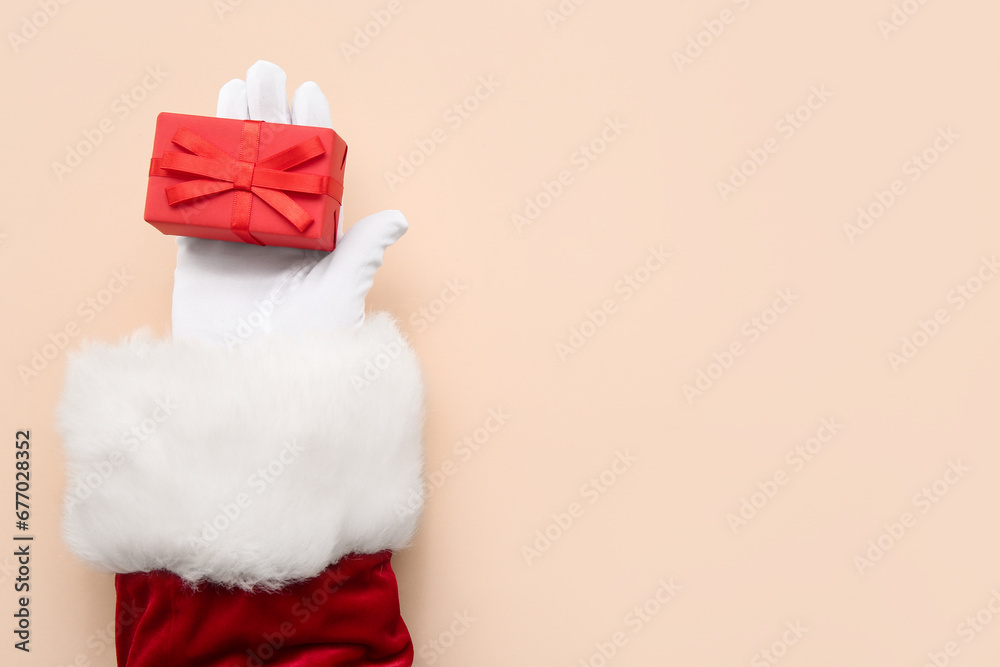 Santa Claus with red gift box on beige background