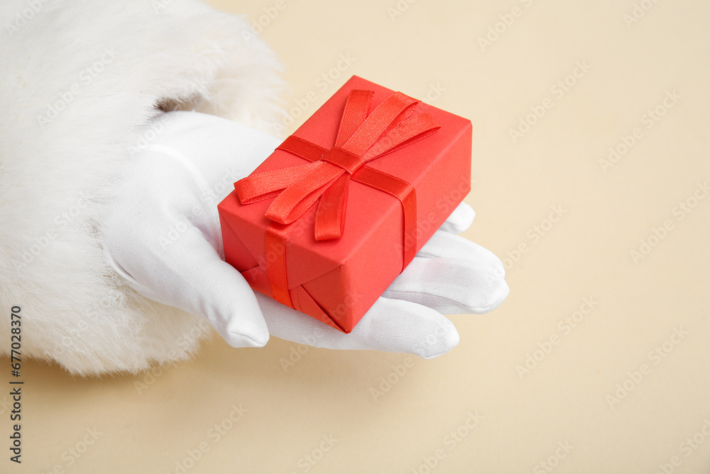 Santa Claus with red gift box on beige background