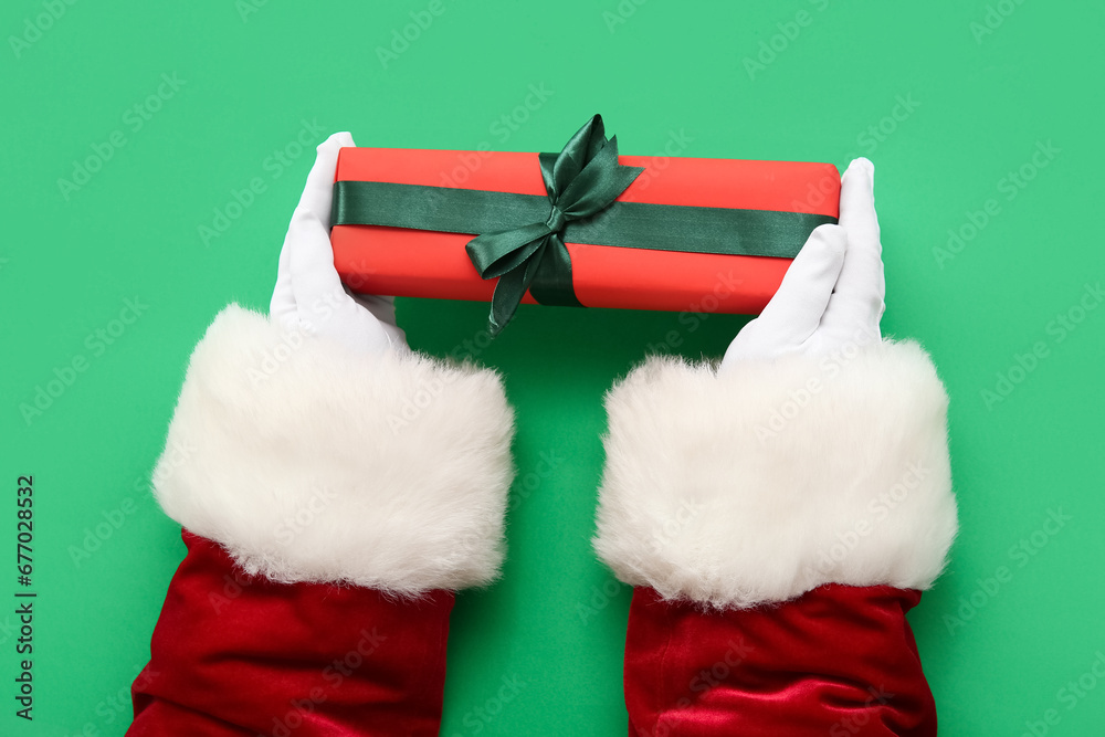 Santa Claus with gift box on green background