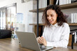 © Stella - Happy smiling beautiful woman with curly hair working with laptop computer, female officer staff having conference meeting online. worker not in the office but able to work, mobile office concept.