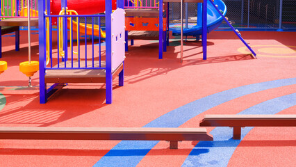 Kid's balance beams with playground climbing equipment on colorful rubber floor in outdoors playground area at kindergarten school