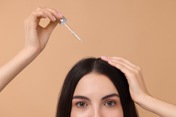 Poster - Woman applying hair serum on beige background, closeup. Cosmetic product