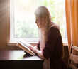 Girl reading a book by the window