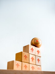 Poster - Target icon on wooden sphere on top of cube blocks bar graph chart steps with up arrows symbol on desk, white vertical background. Investment, income, revenue, profit goal, business growth concepts.