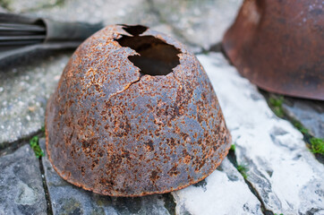 The old rusty soldier's helmet of the Soviet soldier of World War II lies on a stones. Soldier's cemetery