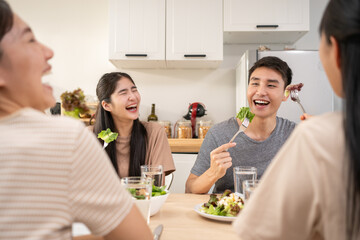 Happy Asian friends lunching with healthy food home- Young people having fun eating meal and drinking water for lunch.