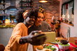 © Marko Geber - Lesbian couple taking selfie during christmas dinner at home