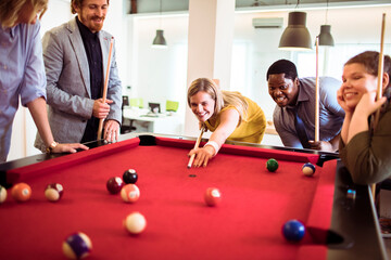 Poster - Office workers playing pool together. Young man and woman playing billiards after work