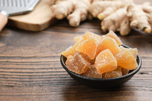 Bowl Of Candied Ginger Pieces And Ginger Roots On Wooden Kitchen Table.