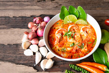 Tom Yum Goong Or Shrimp Soup Spicy Sour Soup Traditional Food In Thailand Contains Chili, Lime,lemongrass, Lime Leaf, Along With Cooked Rice In A White Dish On The Old Wood Background.