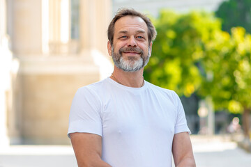 A handsome European man with a beard 50-55 years old smiles happily on the street