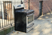 Thrown Out Used Steel Stove Oven On The City Street Sidewalk As Left As Garbage Pickup Or Abandoned 