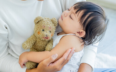 Baby innocent adorable little girl hug by mother, holding doll, comfortable, well sleeping in a day, staying in house or apartment. Kid, Healthcare Concept.