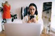 © BullRun - Focused woman using smartphone in atelier