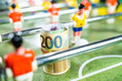 Close up shot of a roll of euro money bills placed on the green plastic field of a table football game, concept of European football, transfers, betting and gambling