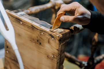 A man is a professional carpenter, a woodworker, applying putty and cement to a wooden chair in the workshop. Photography, handmade concept.