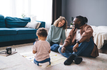 Happy diverse family with kid sitting on floor near sofa at home