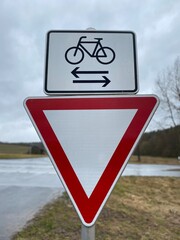 Vertical shot of the Yield and bicycle street signs seen by the side of the road