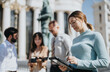 © qunica.com - Business professionals collaborate outdoors in the city. They develop strategies for business expansion, financial planning, and market research.