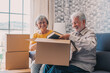 © Daniel - Relaxed mature married couple in love resting on couch among paper cardboard boxes, taking break, pause, hugging, talking, enjoying being in new home. Real estate concept.