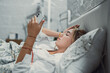 © Daniel - Top view unhappy woman feeling headache after sudden awakening by phone call, message signal or alarm in early morning, exhausted young female suffering from insomnia or migraine, lying in bed.