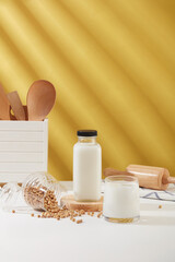 Wall Mural - Kitchen concept with some wooden utensil displayed with unbranded bottle and cup of milk on white table. Nuts have been shown to promote weight loss. Mockup design