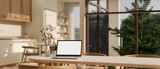 Fototapeta  - A laptop mockup on a dining table in a beautiful Scandinavian kitchen in a modern spacious home.