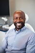 Close-up photo of a smiling African American man sitting in a chair in a dental office. He is waiting for the dentist for an oral procedure. Teeth whitening concept.