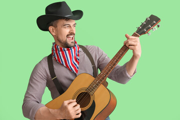 Wall Mural - Handsome cowboy playing guitar on green background