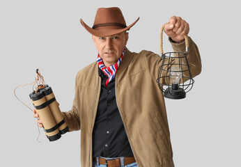 Wall Mural - Mature cowboy with explosive and lantern on light background