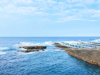 beautiful seascape landscape view at seashore bay with blue sea ocean wave and man-made rock breakwater reef in nature sky background