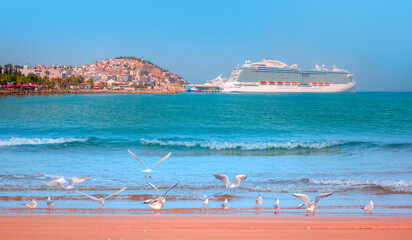 Wall Mural - Panoramic beach landscape, Empty tropical beach and turquoise seascape - The cruise ship is located on Kusadasi Island in the port of Kusadasi, Turkey
