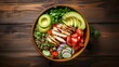 Healthy salad bowl with quinoa, tomatoes, chicken, avocado, lime and mixed greens (lettuce, parsley) on wooden background top view. Food and health.