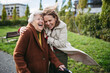© Halfpoint - Grandmother and mature granddaughter on a walk in city park, during windy autumn day. Caregiver and senior lady enjoying the fall weather, laughing as the wind blows their hair.