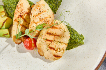 Sticker - Macro shot in a top view of grilled chicken fillet with avocado and spinach, revealing the texture and details of this healthy dish. Grey concrete background with hard shadows adds a modern touch