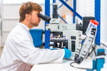 Wall Mural - scientist looking into a microscope sitting on a laboratory