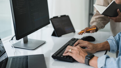 Wall Mural - two developer programmer typing code while discussing about programming to developing website