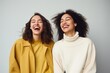 Two interracial best friends laughing and having a good time together in a studio. Portrait of lovely young women, beautiful, diversity, smiling isolated on pastel background.