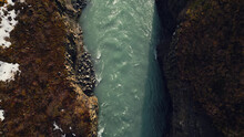 Aerial view of icelandic waterfall in river canyon, spectacular nordic scenery with water stream flowing between hills. Beautiful landscape in iceland with cliffs and fields. Slow motion.