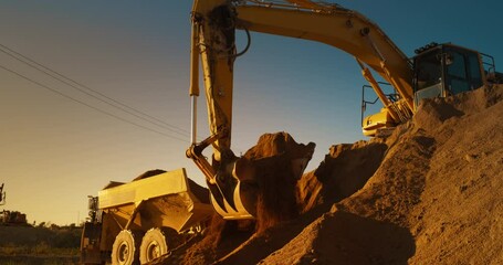 Wall Mural - Construction Site On Sunny Evening: Industrial Excavator Loading Sand Into A Truck. The Process Of Building New Apartment Block. Workers Operating Heavy Machinery To Complete A Real Estate Project.