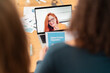© Studio Marmellata - Back view of unrecognizable women looking at laptop screen with image of cheerful woman while on video call meeting over table with charts in modern office