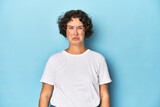 Fototapeta  - Young Caucasian woman with short hair blows cheeks, has tired expression. Facial expression concept.
