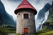 Runder Turm aus Feldsteinen mit einem spitzen Dach aus Ziegeln, umgeben von hohen Gebirge Bergen und Wasserfällen, ursprüngliche Natur Alpen märchenhaft, Wehrturm, Wohnturm