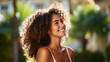 © wetzkaz - Curly-haired woman in a white shirt smiles under the sun, enjoying the park's greenery, exhibiting multiracial beauty.