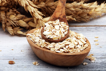 Oat flakes or rolled oats and golden ears of wheat. Healthy lifestyle, healthy eating, vegan diet concept