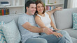 © Krakenimages.com - Beautiful couple watching tv sitting on sofa at home