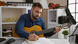 Fototapeta  - Young hispanic man musician composing song playing classical guitar at music studio