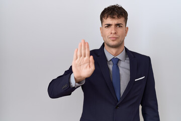 Canvas Print - Young hispanic business man wearing suit and tie doing stop sing with palm of the hand. warning expression with negative and serious gesture on the face.