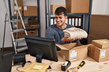 Poster - Young hispanic man ecommerce business worker preparing clothes package at office