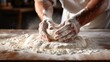 Close up of baker hands clapping and sprinkling white flour to preparing dough in bakery kitchen.